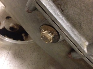 Close-up of the oil drain plug, the hex bolt stripped from attempts to remove it